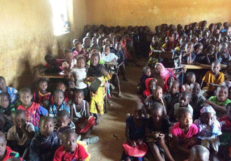 Une salle de classe comble, les élèves serrés sur leurs bancs.